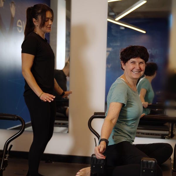 Woman and trainer doing Reformer Pilates at Vive Fitness